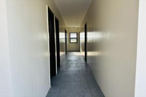 a hallway with black doors and a tile floor at Selline Bed and Breakfast in Bacnotan