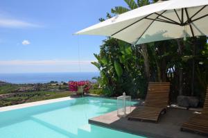 a swimming pool with two chairs and an umbrella at La casa del panorama in Valverde
