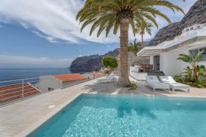 einen Pool mit einer Palme und dem Meer in der Unterkunft La Casa de Los Gigantes in Acantilado de los Gigantes