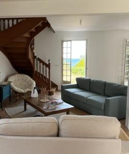 Una sala de estar con un sofá azul y una mesa. en Maison Familiale vue mer et plage à pieds, en Ploubazlanec