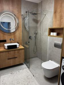 a bathroom with a shower and a toilet and a sink at Japandi Apartment Pogórze in Pogórze +3 photos