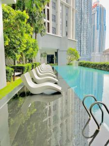 a row of white chairs sitting next to a pool at Luxury Suites At The Mews KLCC in Kuala Lumpur