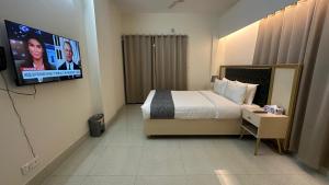 a hotel room with a bed and a flat screen tv at Royal Regent Suites Dhaka in Dhaka