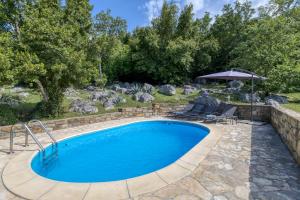 a swimming pool with chairs and an umbrella at Holiday House Kapitani in Hum
