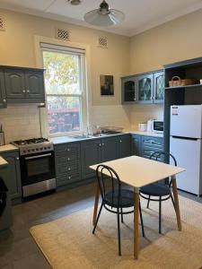 a kitchen with green cabinets and a table and chairs at Executive Cottage, Luxe 1930s Stay in the Heart in Albury