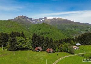 una collina verde con case e montagne sullo sfondo di Cozy Qorte a Lentekhi