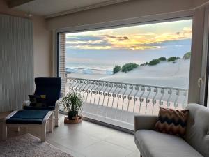 a living room with a large window with a view of the ocean at a'Mare - Valparaiso Koksijde in Koksijde