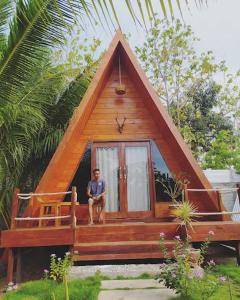 a man sitting on the porch of a small house at Aikoli Kang Resort in Miafeng +5 photos