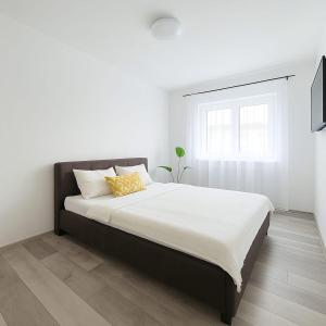 a bedroom with a large bed with white sheets and a window at Casiana Apartments in Timişoara