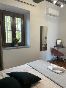 una camera da letto con un letto, una finestra e una sedia di Casa Fioroni Langhe Apartments a La Morra