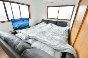 1 cama con sábanas blancas en una habitación con ventanas en Tomoko's旅館, en Izunokuni