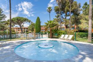 een klein zwembad met twee stoelen en palmbomen bij Résidence Pierre & Vacances La Pinède in Hyères +47 foto's