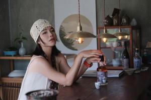 a woman sitting at a table with a bottle of wine at Come to Xipuman B&B in Baishi