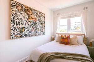 a bedroom with a bed with a large painting on the wall at Ocean Views at The Holkham Fairy Bower in Sydney
