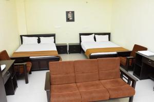 a room with two beds with a chair and a desk at RDS Guest House Bypass in Āmbūr