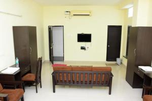 a room with two desks and a bench and a tv at RDS Guest House Bypass in Āmbūr