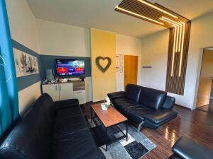 ein Wohnzimmer mit einer schwarzen Ledercouch und einem Tisch in der Unterkunft Comfort & Relax mit Sky & PlayStation - Haus Burgstadt in Altena + 14 Fotos