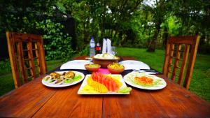 a wooden table with plates of food on it at Golden Rock Retreat Sigiriya in Sigiriya