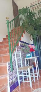 a staircase with two white chairs and a green rail at Casa El Azahin in Cazalla de la Sierra