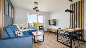 a living room with a blue couch and a table at SOLE MARE Apartamenty Piamola in Kąty Rybackie