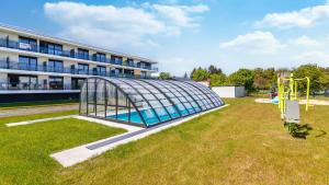a swimming pool in a glass greenhouse in front of a building at SOLE MARE Apartamenty Piamola in Kąty Rybackie