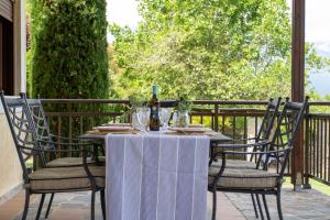 a table with chairs and a bottle of wine on a porch at Zeusplace Villa Divina Montagna in Neos Panteleimonas