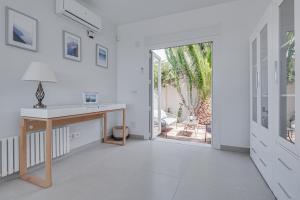 Dieses weiße Zimmer verfügt über einen Schreibtisch und eine Glasschiebetür. in der Unterkunft Villa Serena Marbella-Elviria in Marbella + 43 Fotos
