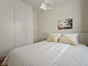 a white bedroom with a large white bed with pillows at 46m2 - Location - Parking space - Sauna - Self check-in in Jyväskylä
