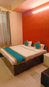Un dormitorio con una cama grande con una pared roja. en Hotel SwasthiK Residency, en Dehradun 9 fotos más