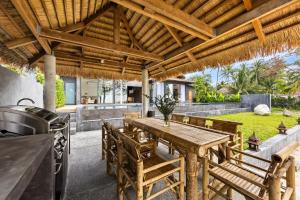 an outdoor kitchen with a wooden table and chairs at Private Beach Villa With Sunset Views-On The Sand in Amphoe Koh Samui