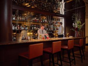 a man standing at a bar with a bartender at Rocco Forte The Charles Hotel in Munich