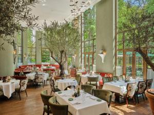 a restaurant with tables and chairs and windows at Rocco Forte The Charles Hotel in Munich