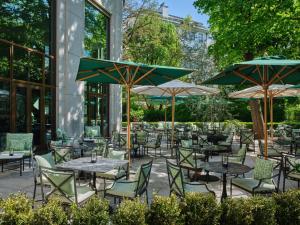 an outdoor patio with tables and chairs and umbrellas at Rocco Forte The Charles Hotel in Munich +29 photos