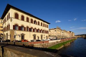 budynek nad rzeką, przy którym zaparkowane są samochody w obiekcie Leone Blu Suites | UNA Esperienze we Florencji