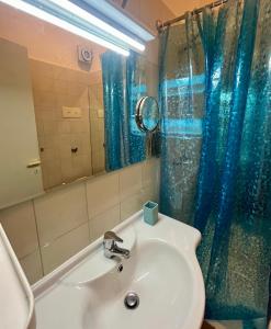 a bathroom with a sink and a blue shower curtain at Excelsior Relaxing Apartment in Levanto