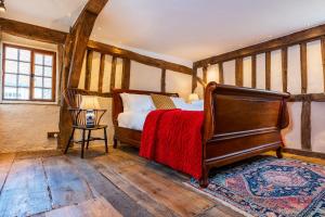 ein Schlafzimmer mit einem Bett mit einer roten Decke in der Unterkunft Taper House - Cosy Medieval Cottage in Kersey