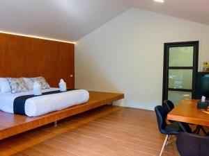 a bedroom with a bed with a wooden headboard and a desk at Green Love Garden Resort in Ban Bung Mai