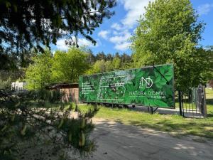 zielony znak na boku płotu w obiekcie Natura Domki Anastazewo w mieście Anastazewo