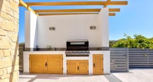 una cucina all'aperto con porte gialle e una griglia di Villa 347 Meo - Fantastic Five Bedroom Villa with Private pool in Peaceful Location, Aphrodite Hills a Kouklia