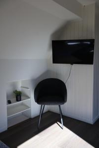 a black chair in a room with a tv at Hotel de Abdij in Horn
