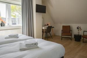 a hotel room with two beds and a tv at Hotel-Restaurant De Walvisvaarder in Hollum