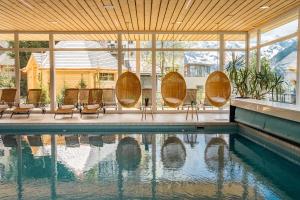 翁根Braunbär Hotel & Spa - Former Alpine Sunstar Hotel的一座房子,四周设有游泳池,周围设有椅子