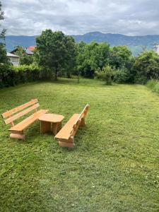 two wooden benches sitting in a field of grass at Butmir house-Sarajevo in Sarajevo +5 photos