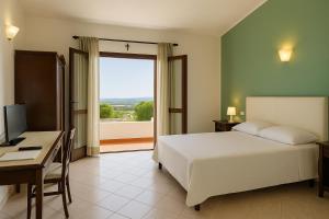 una camera da letto con un letto, una scrivania e una finestra di Agriturismo Nuraghe Tuttusoni a Aglientu