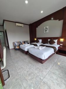 a hotel room with two beds and a chair at New Forest Patong in Patong Beach
