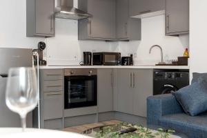 a kitchen with gray cabinets and a blue couch at Charming 1 BR apartment walk to city centre in Belfast