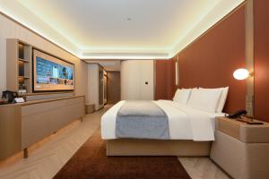 a hotel room with a large bed and a flat screen tv at 西安明城墙永兴坊桔子水晶酒店 in Xi'an