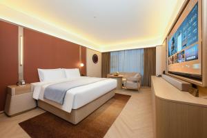 a hotel room with a large bed and a flat screen tv at 西安明城墙永兴坊桔子水晶酒店 in Xi'an