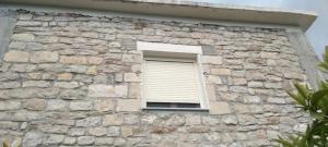 a window in a stone building with a blind at The stone house in Hekal