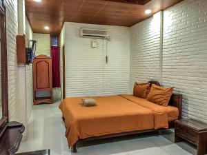 a bedroom with a bed with an orange blanket at Arys Garden Hotel Yogyakarta in Yogyakarta